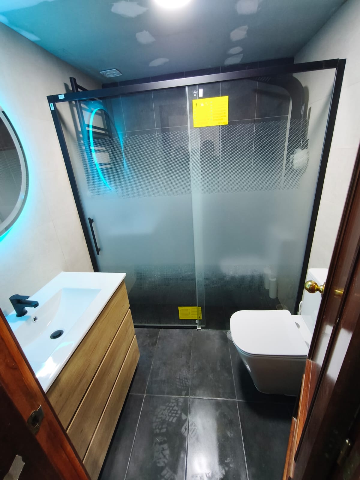 Baño moderno con mampara negra en Madrid - HG Reformas